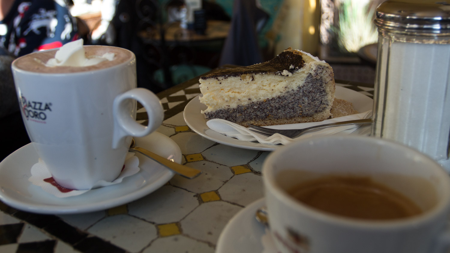 Warme chocolademelk met slagroom en een taartje op een tafel in Cafe Kasbah in Dusseldorf