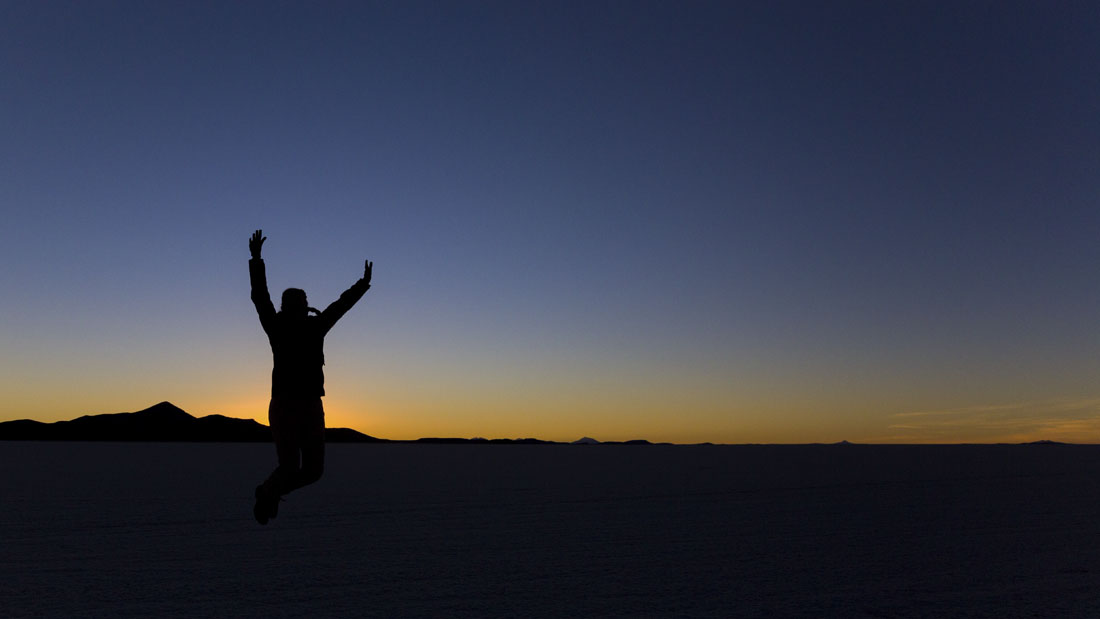 Iemand springt in de lucht tijdens de Zonsondergang op Salar de Uyuni