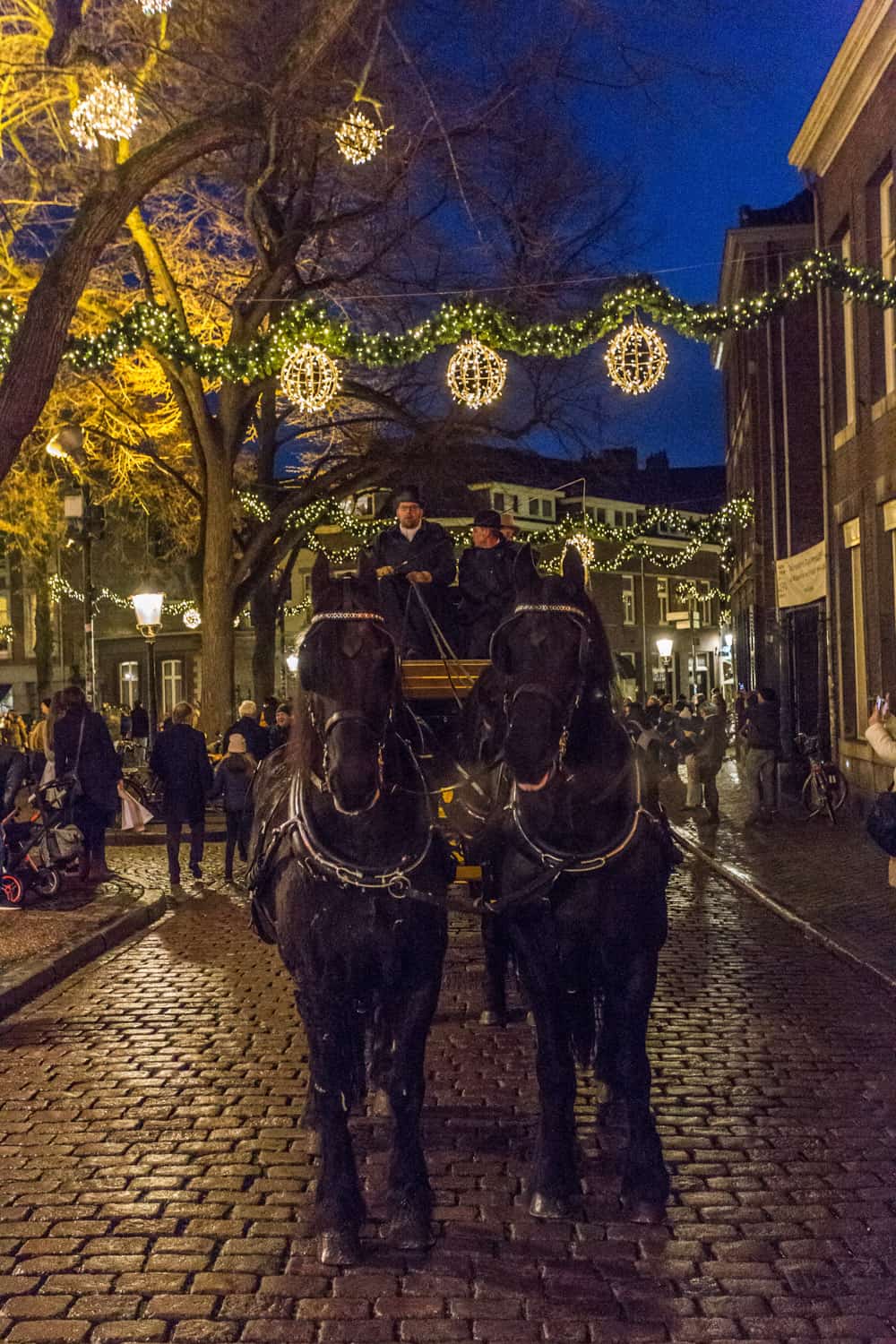 Intocht van de kerstman in Maastricht: wagen met zwarte paarden en kerstverlichting