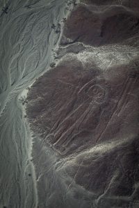 De astronaut op een berg met een arm omhoog om te zwaaien. Het mannetje is een van de Nazcalijnen.