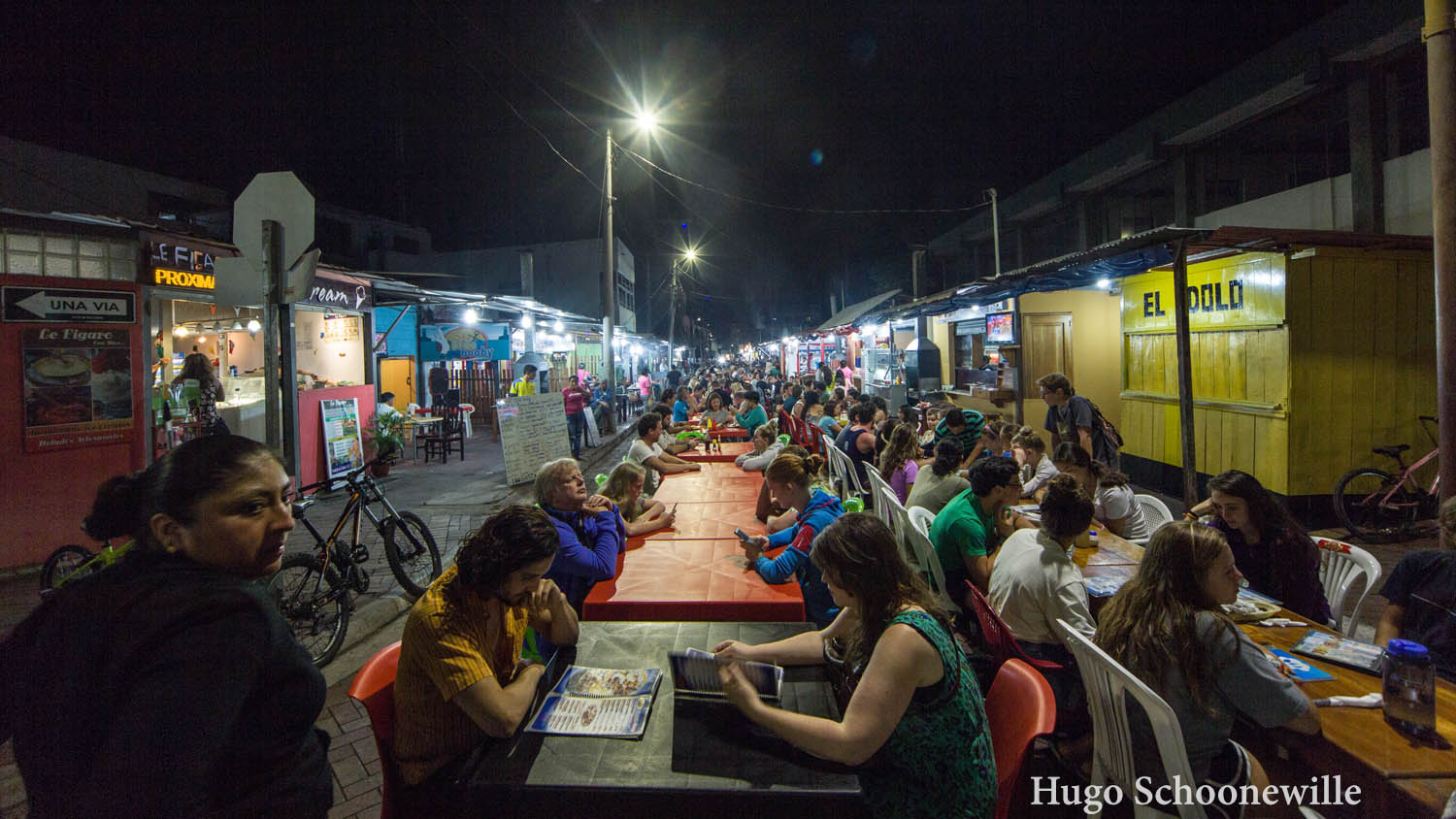 Mensen aan tafeltjes midden op straat in Puerto Ayora op het eiland Santa Cruz op de Galápagos.