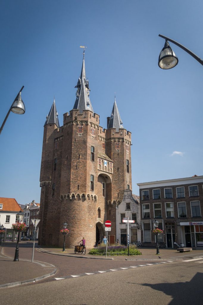 De indrukwekkende Sassenpoort, overblijfsel van de stadsmuur van Zwolle, met torens en een blauwe lucht.