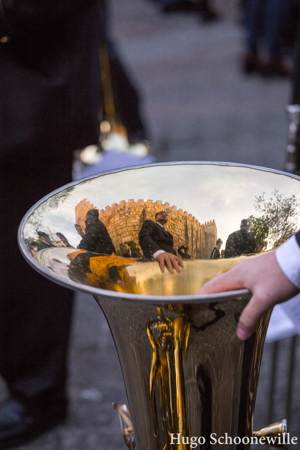 Muzikant houdt zijn tuba vast op de grond en in de hoorn weerspiegelt het Alcazar van Sevilla