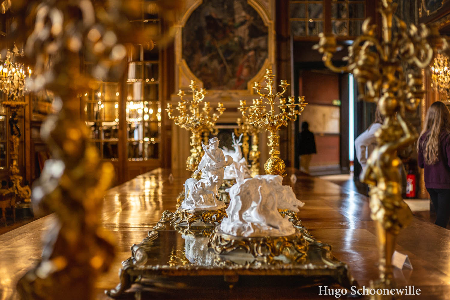 Beeldjes en gouden kandelaren op een lange tafel in een zaal in het kasteel van Chantilly.