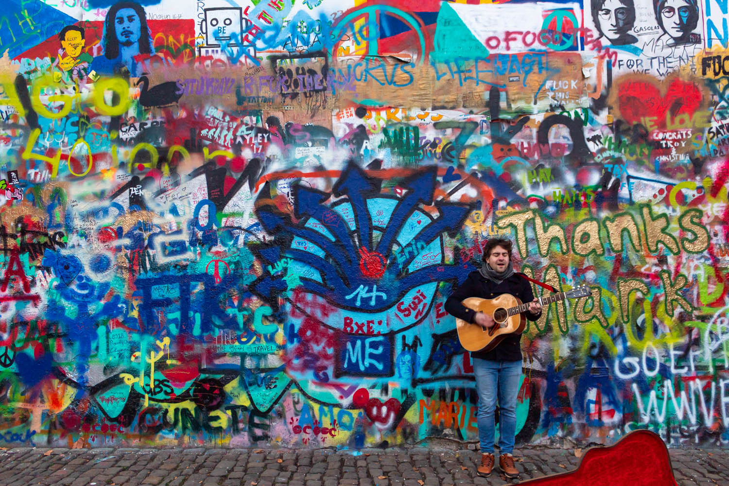 Beschildere John Lennon Wall in Praag met ervoor een muzikant met een gitaar