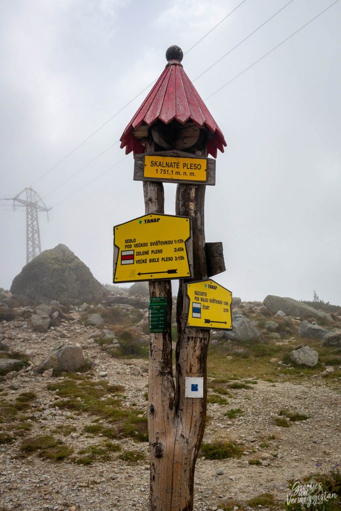 Een paal met allerlei gele bordjes die verschillende routes aangeven bij Skalnaté pleso in het Tatragebergte.