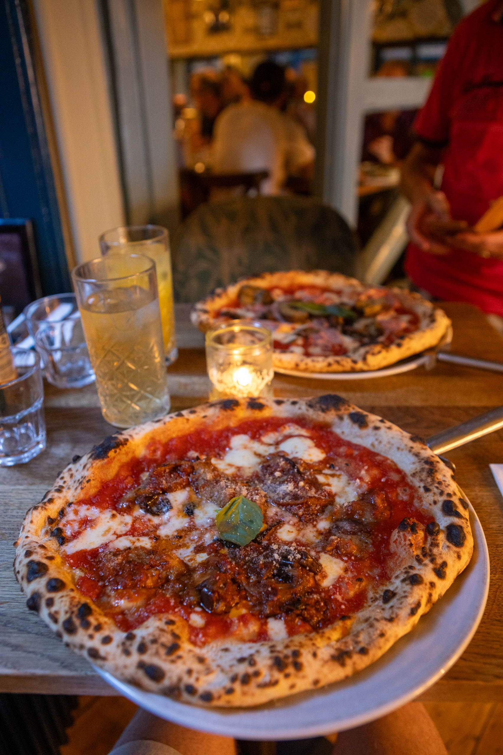 Bord met pizza op een tafeltje in Pizzeria Luca met een kaarsje ernaast