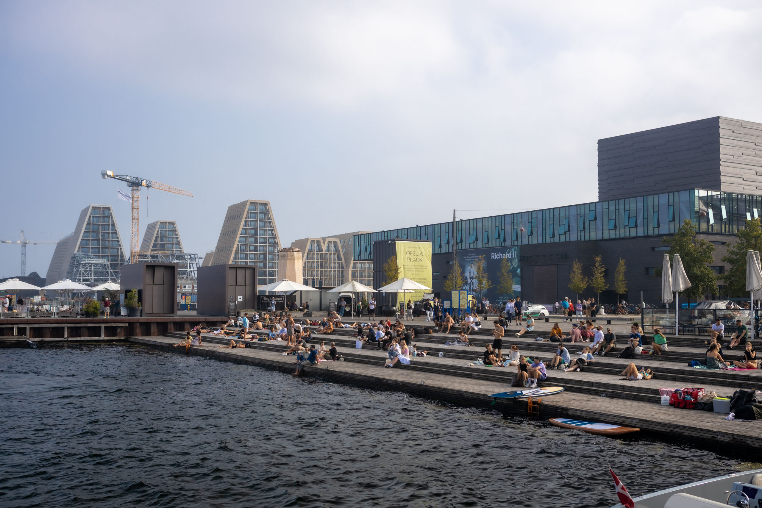 Mensen zitten lekker in de zon te eten op Kyssetrappen, trappen die aflopen naar het water in Kopenhagen.
