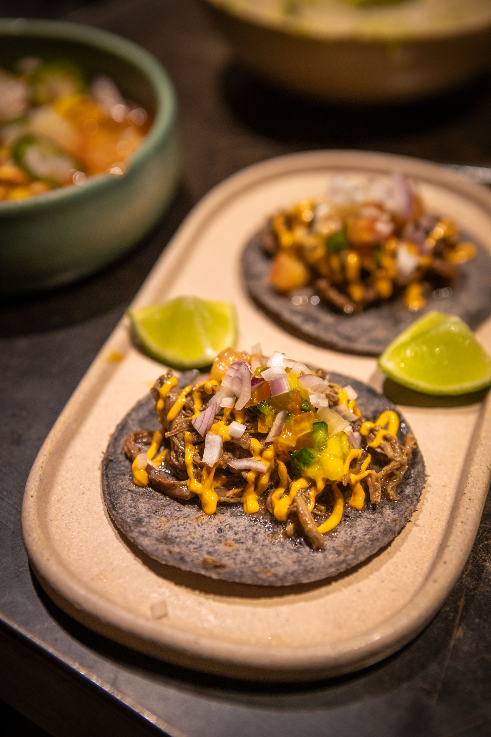 Zwarte tortillas met vulling op ovaal bord met limoenen ernaast