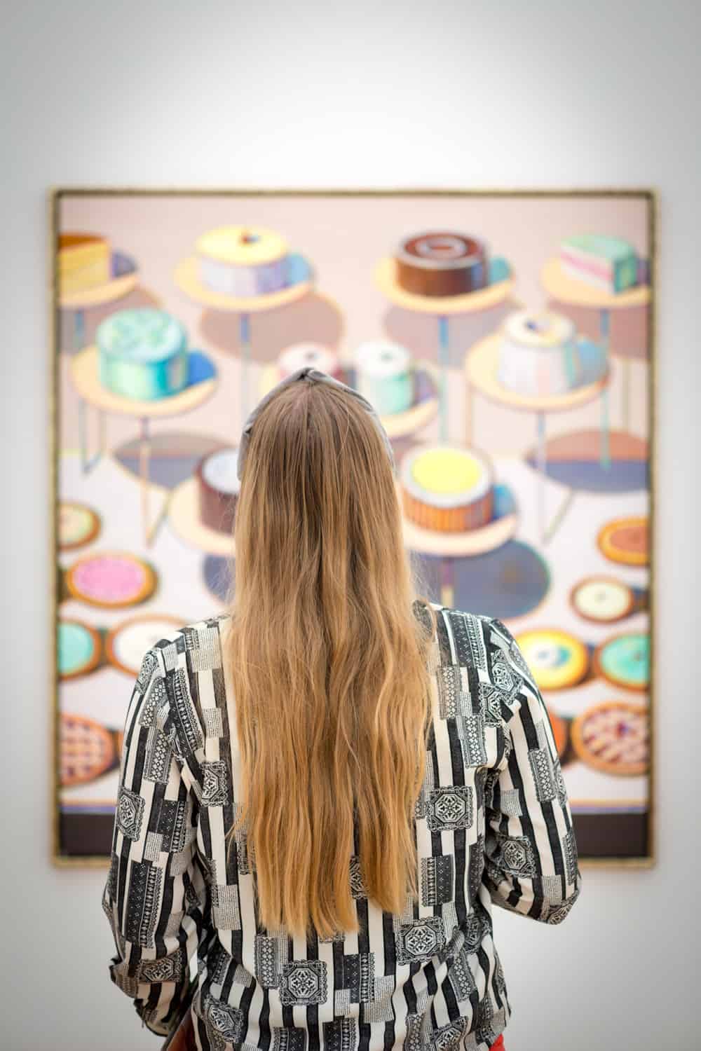Manouk met lang blond haar voor een schilderij van taartjes in Museum Voorlinden