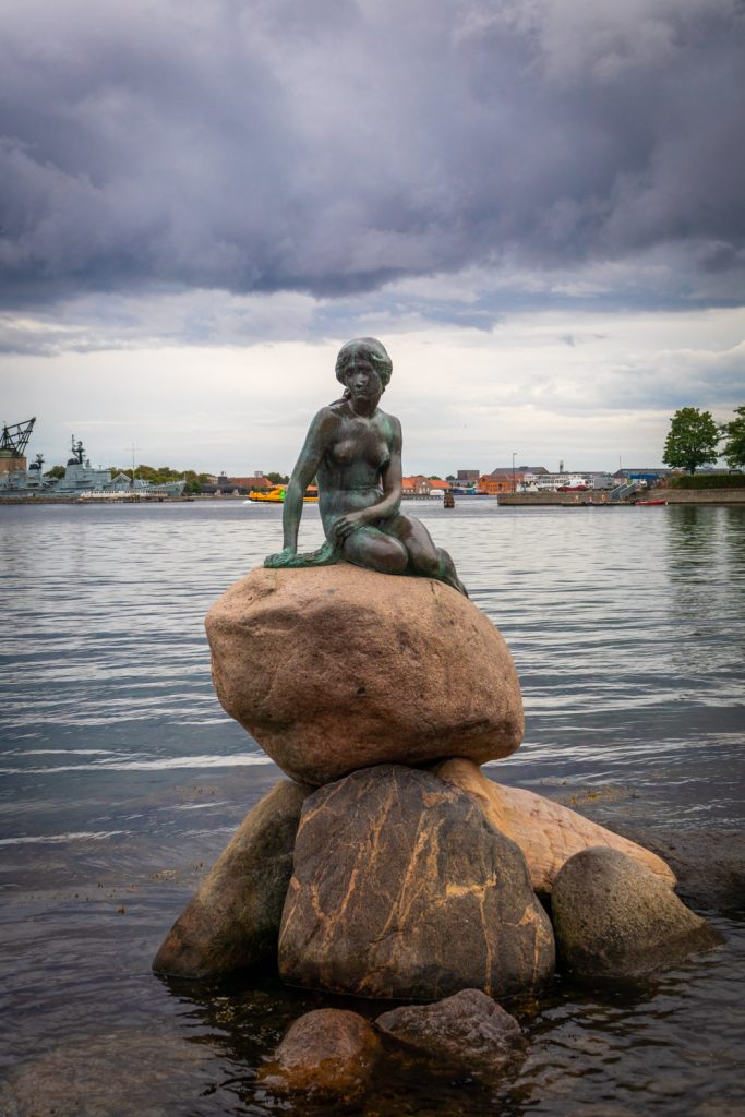 Kleine Zeemeermin in Kopenhagen gezien vanaf de voorzijde, zittend op een rots in het water
