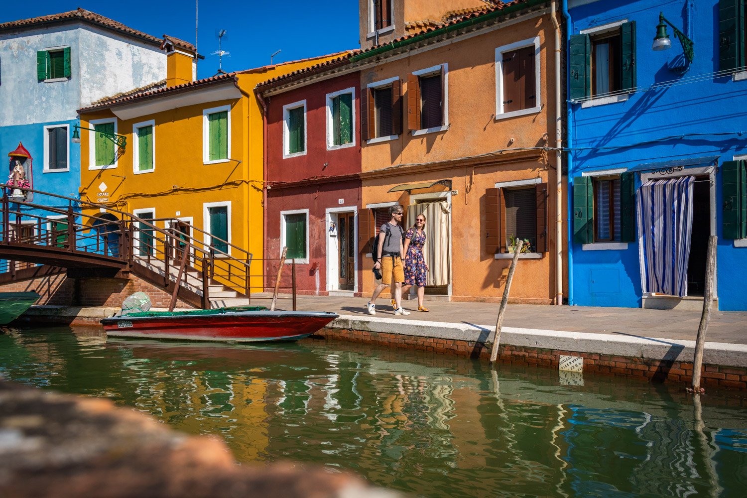 De gekleurde huizen op Burano aan het water met een bruggetje links