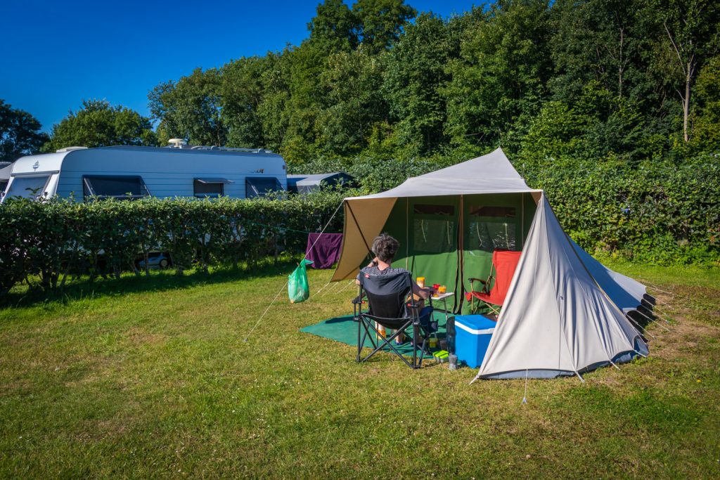 De Waard tent opgezet op een grasveld op een camping met Hugo op een stoel ervoor