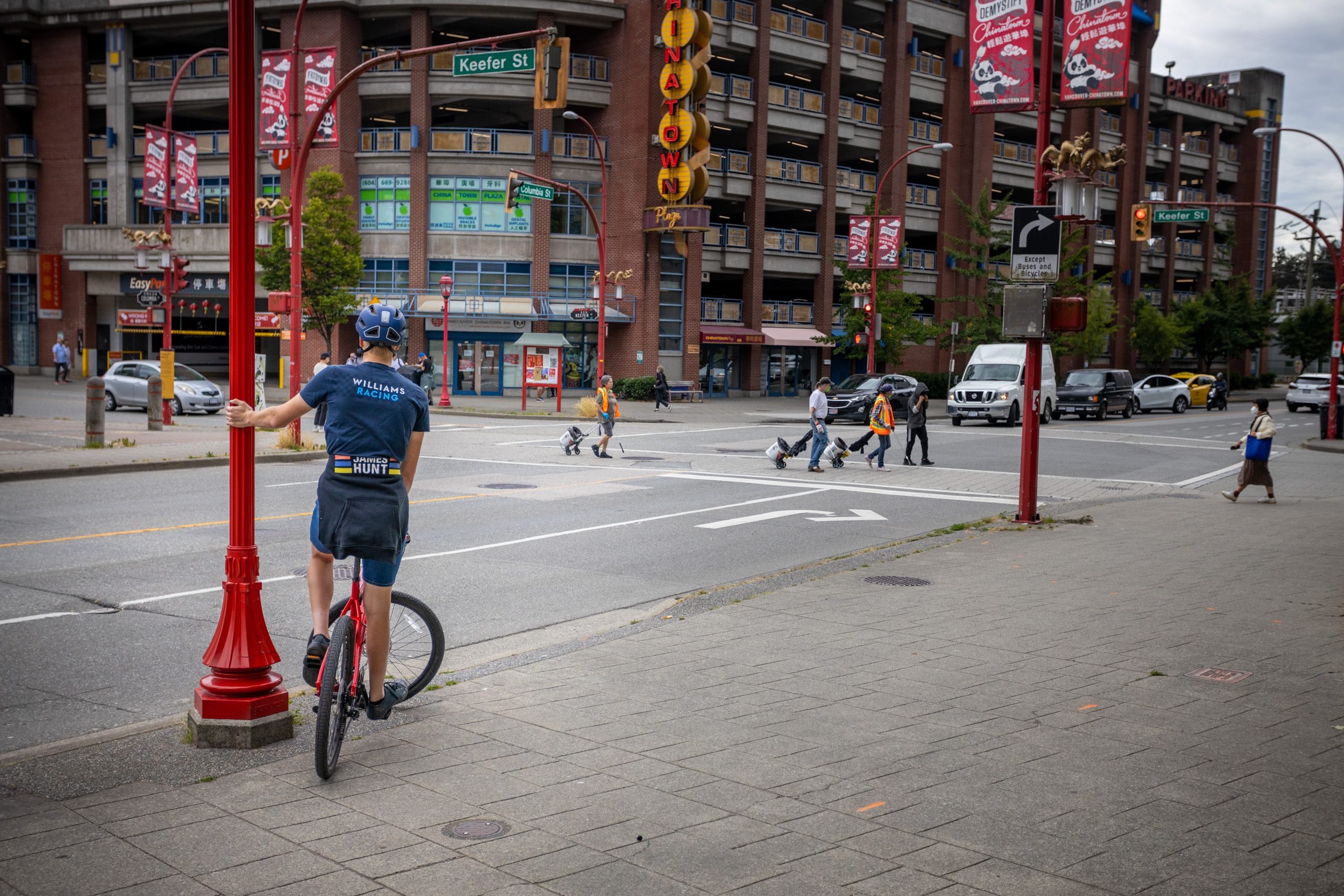 Jongen op fiets leunt tegen rode lantaarnpaal in China Town in Vancouver