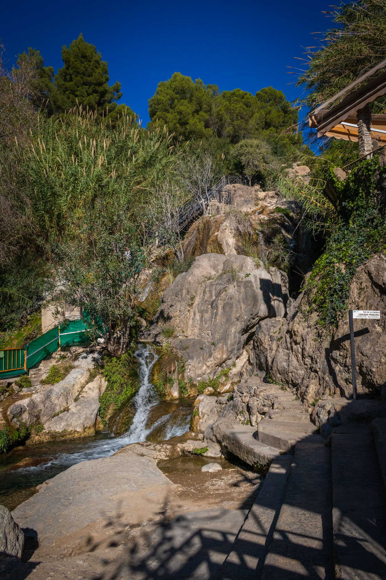 Watervallen langs de rotsen omlaag met een wandelpad ernaast