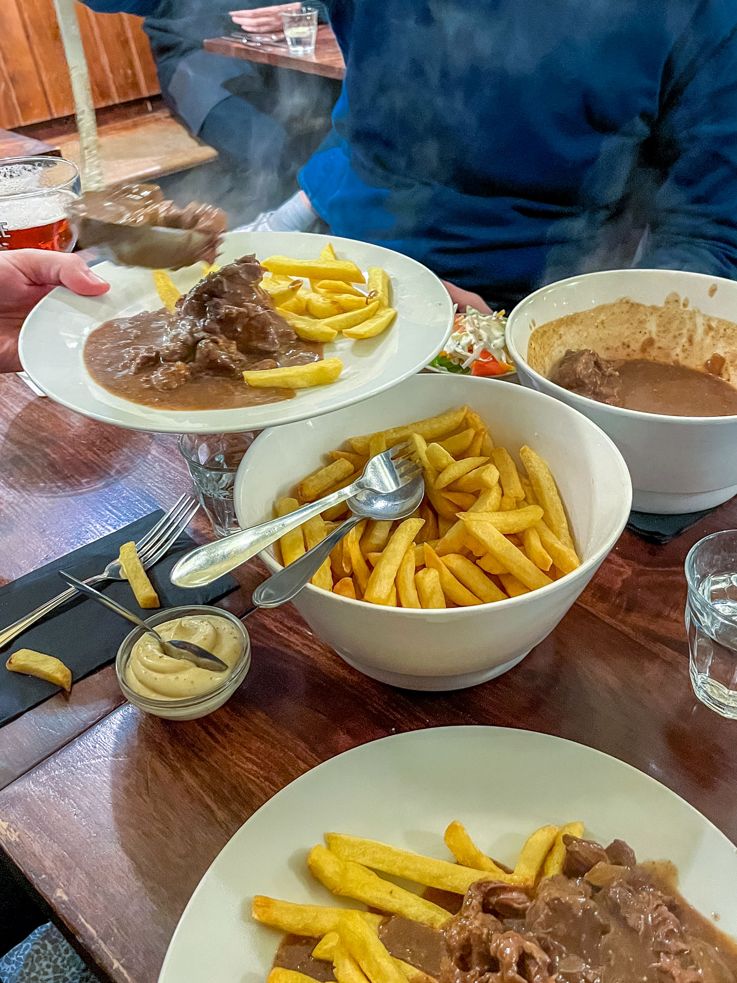 Stoofvlees met friet dat op borden wordt geschept in restaurant De Arme Duivel, perfect voor lekker eten in Antwerpen