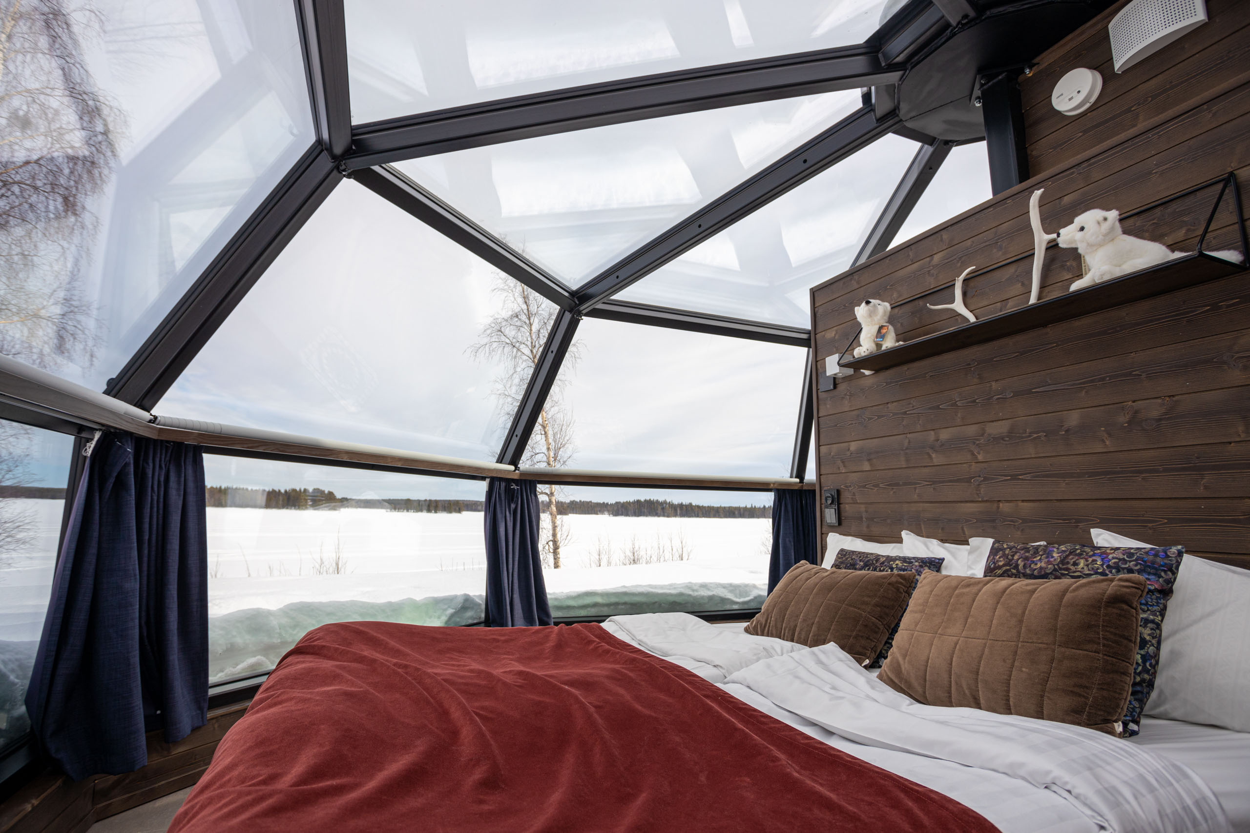 Opgemaakt bed met rode deken in glazen iglo in Rovaniemi op Ranua Resort