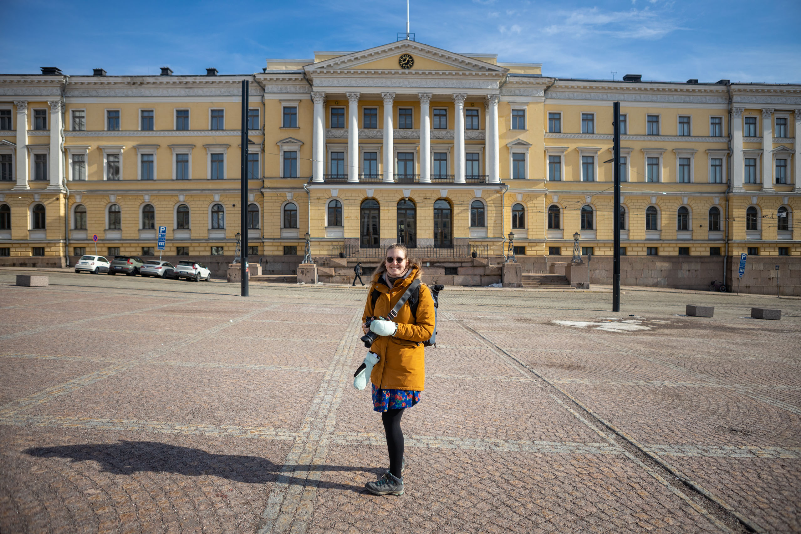 Wat te doen in Helsinki? Manouk staat voor een lichtgeel neoclassisistisch gebouw op het Senaatplein in Helsinki