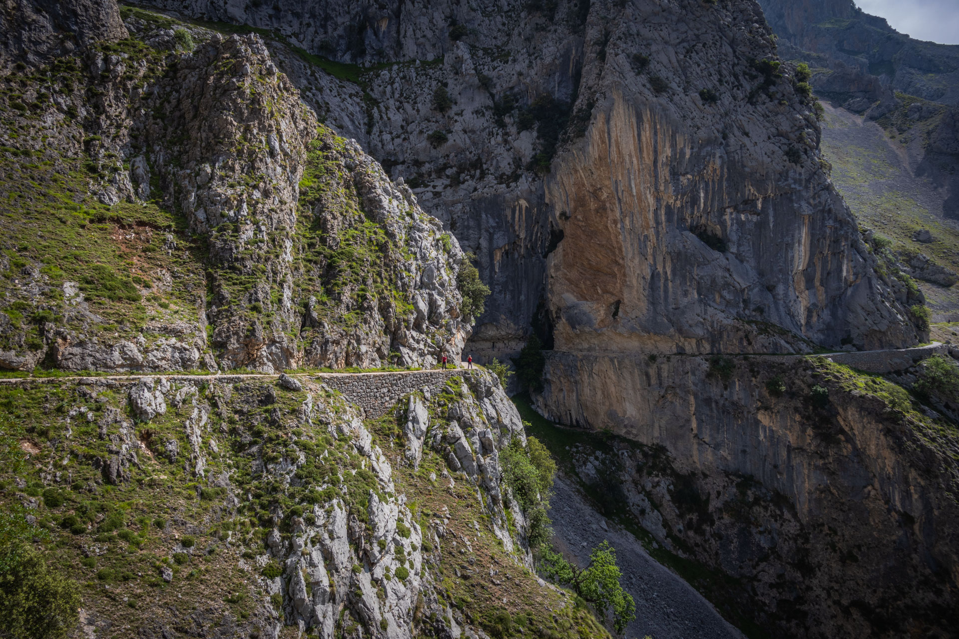 Wandelpad tegen de rotswand tijdens de Ruta del Cares hike in Spanje, waar Hugo in de verte op het pad staat.