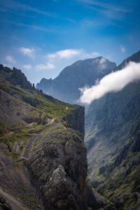 Het pad van Ruta del Cares in Picos de Europa over een bergwand met hoekig uitsteeksel boven de kloof, met blauwe lucht en wolken