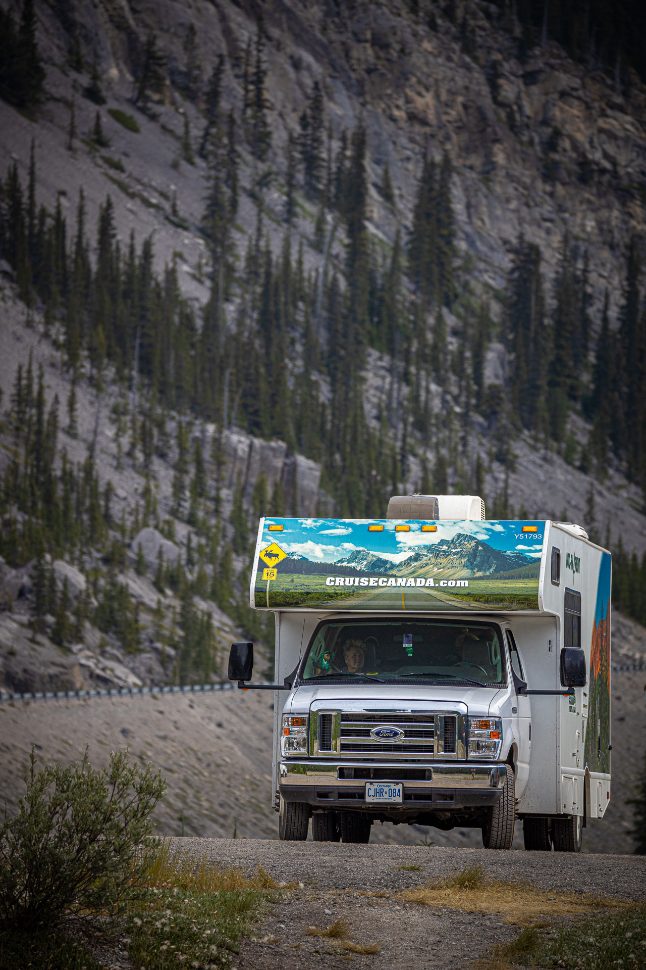 Camper van CruiseCanada met een rotswand erachter op de weg in Canada tijdens een rondreis met camper door Canada