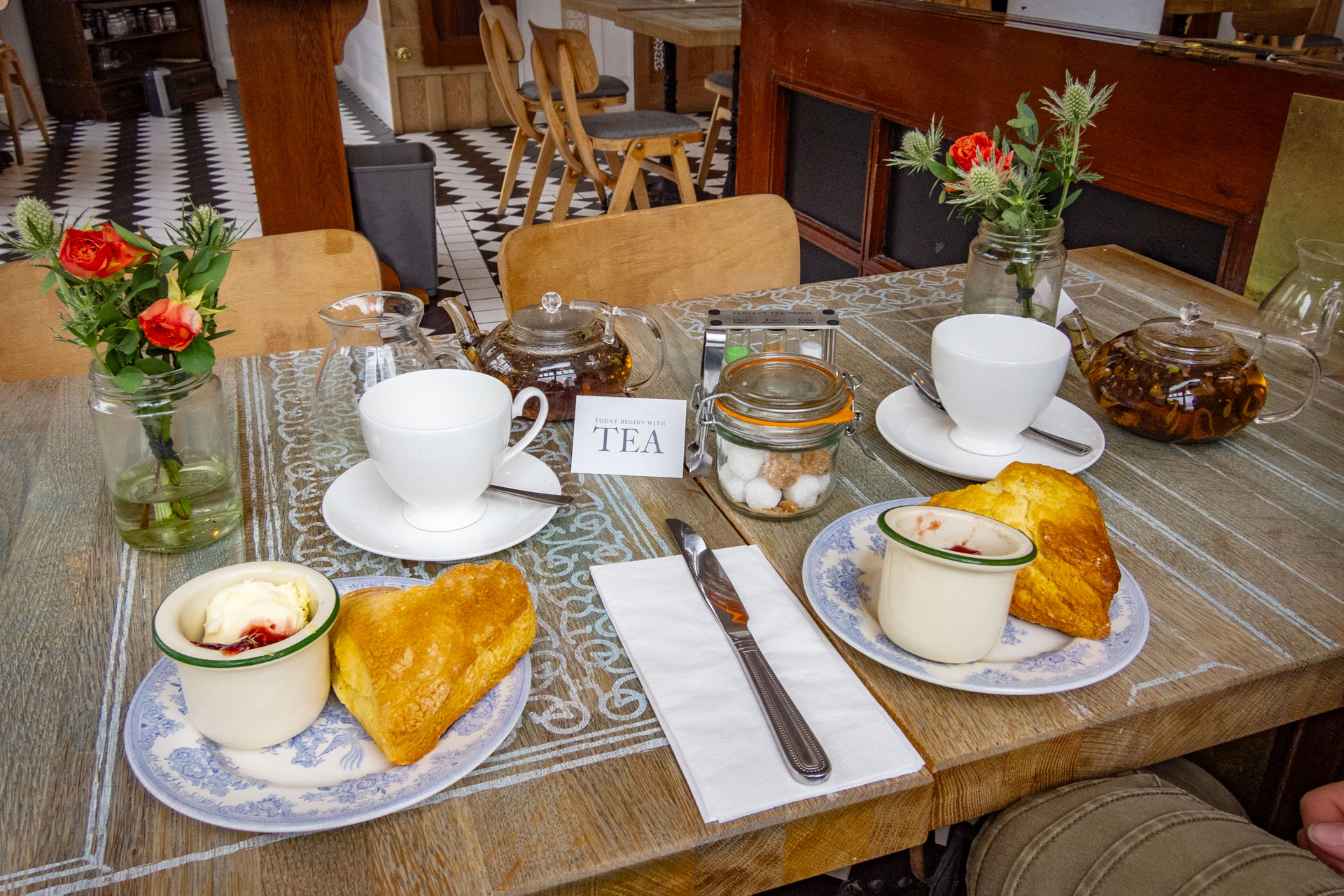 English tea in Manchester: witte kopjes en theepotjes op een tafel met bordjes met hartvormige scones ervoor met clotted cream en jam in bakjes op het bord erbij