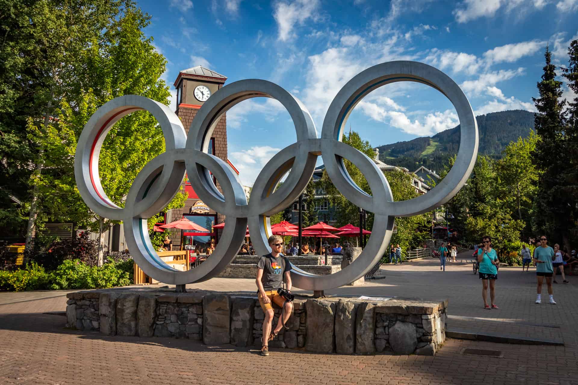 Hugo zit op de rand van de grote zilveren Olympische ringen op Olympic Plaza in Whistler