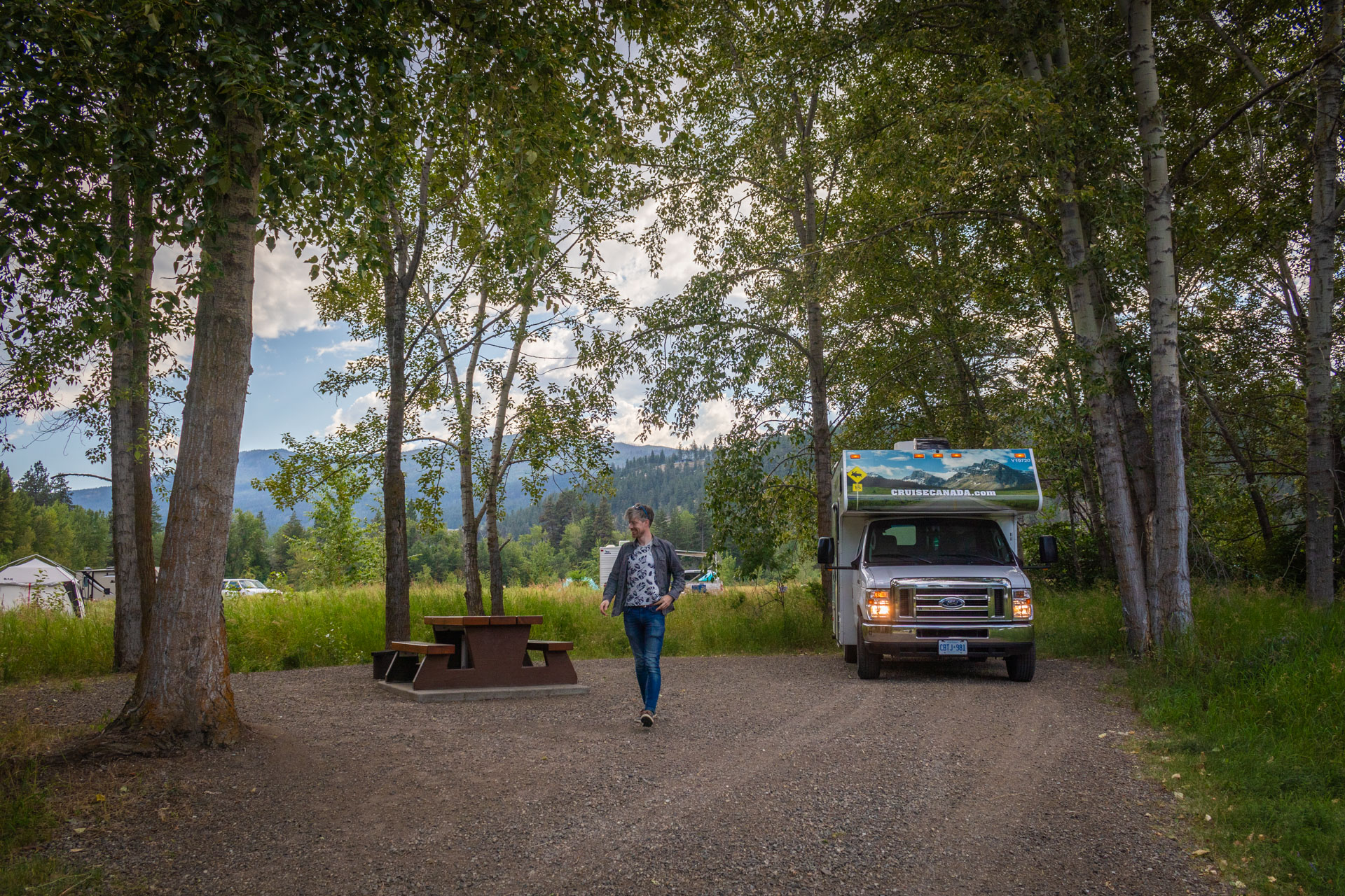 Hugo op een camperplek tussen de bomen met een camper van CruiseCanada naast hem op Fintry Campground, een mooie stop tijdens een rondreis Canada met camper