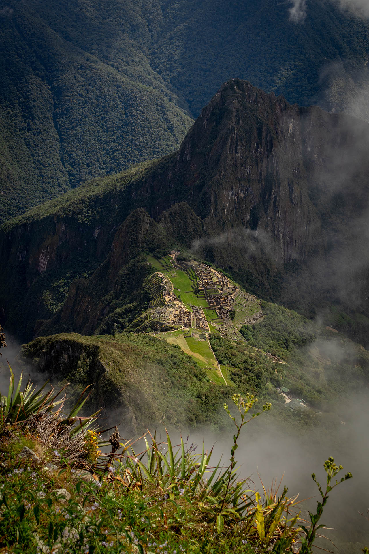 Machu Picchu in de diepte op de berg met mist eromheen gezien vanaf Machu Picchu Mountain