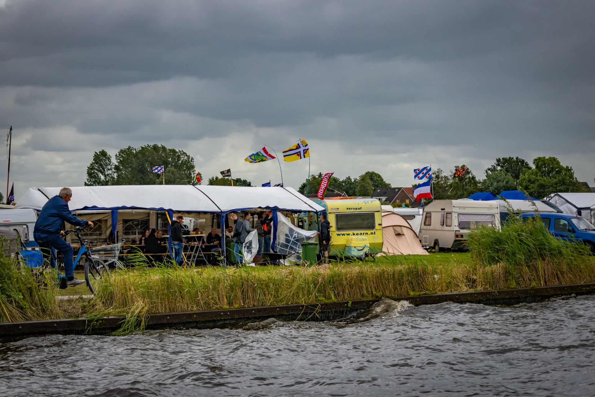 Tenten en caravans bij het Veenhoop festival gezien vanaf het water