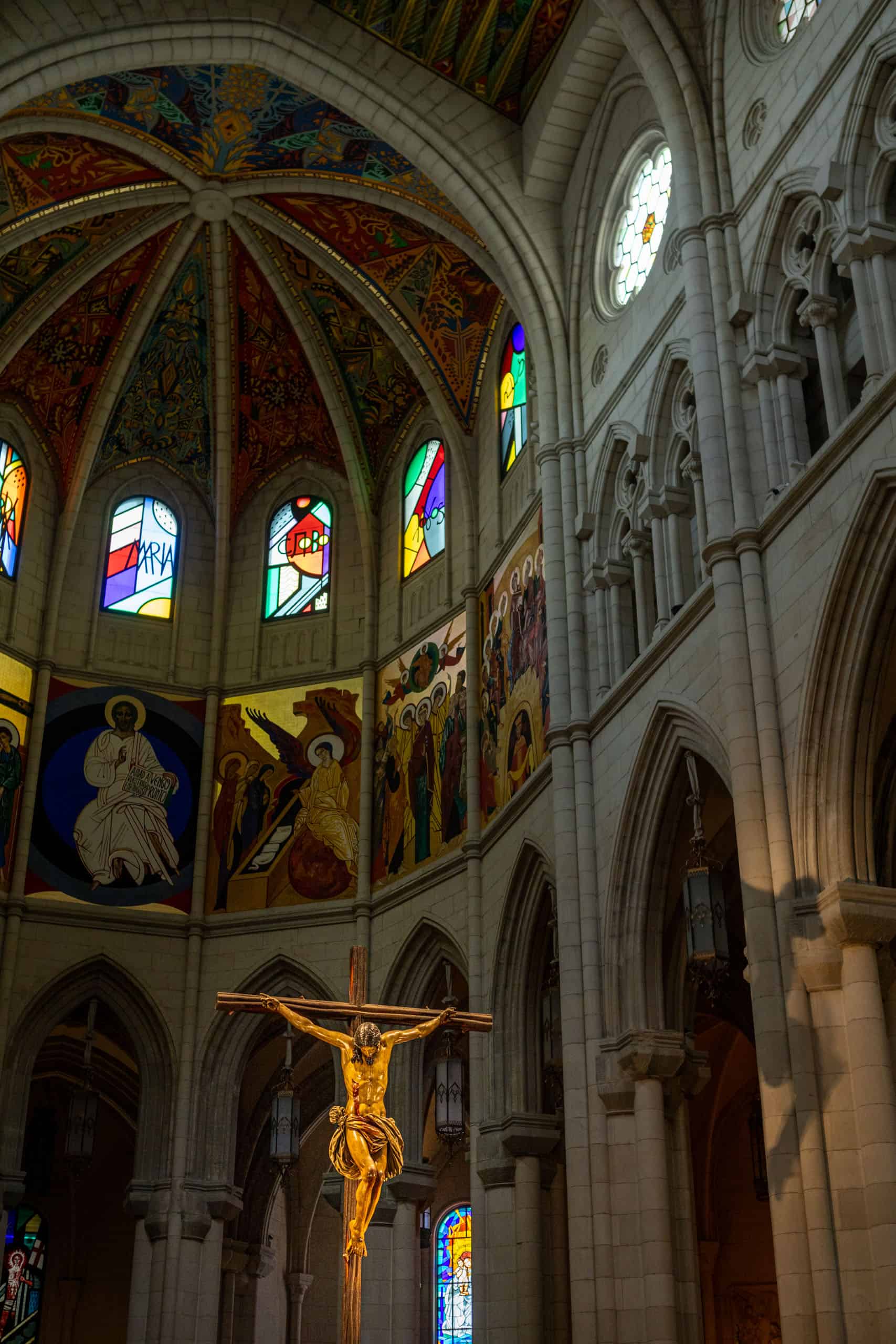 Moderne versieringen en glas-in-loodramen in de kathedraal in Madrid met een uitgelicht Jezusbeeld op het altaar ervoor