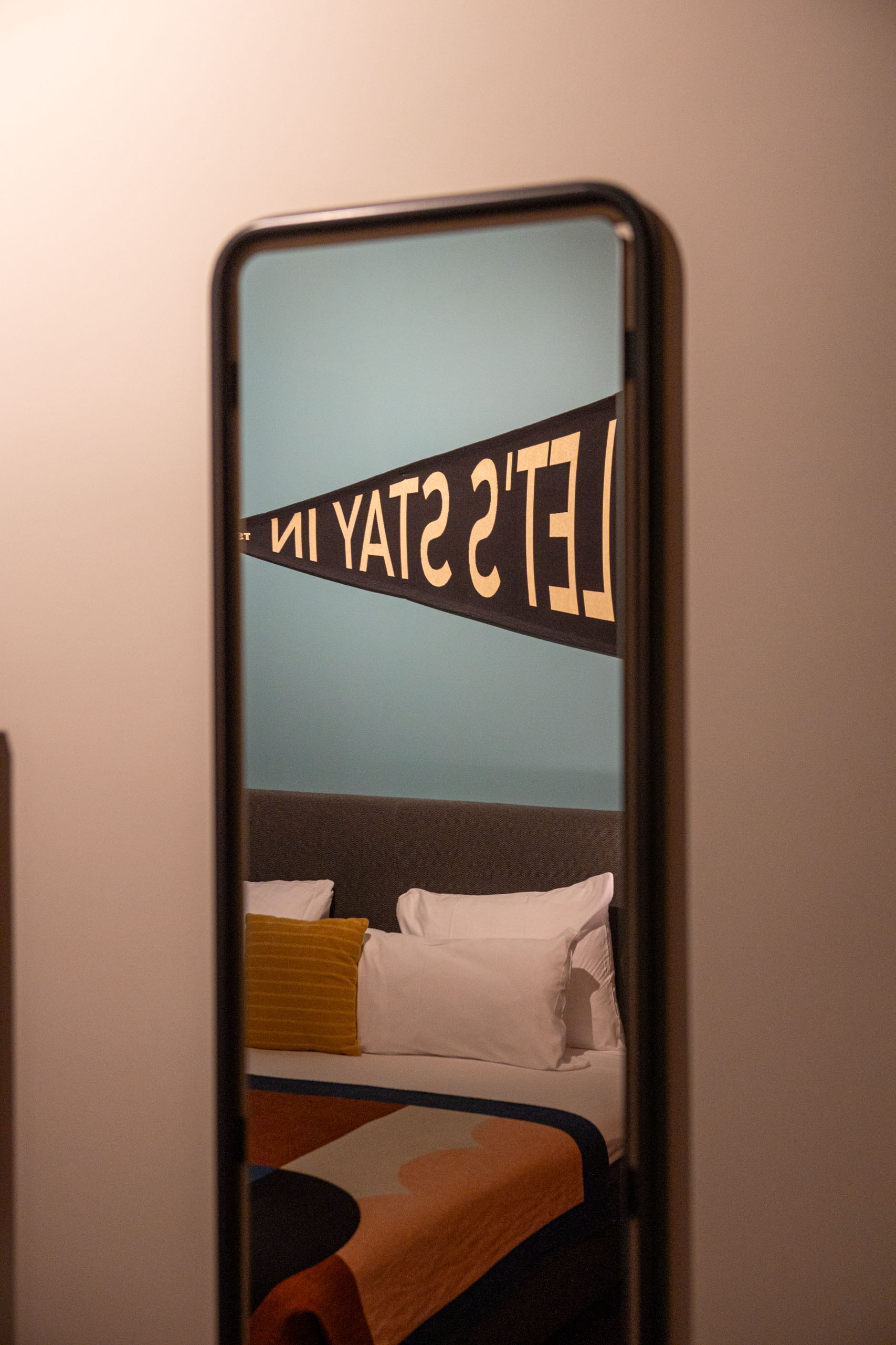 Spiegel waarin je het bed ziet met erboven een banner met Let's stay in erop