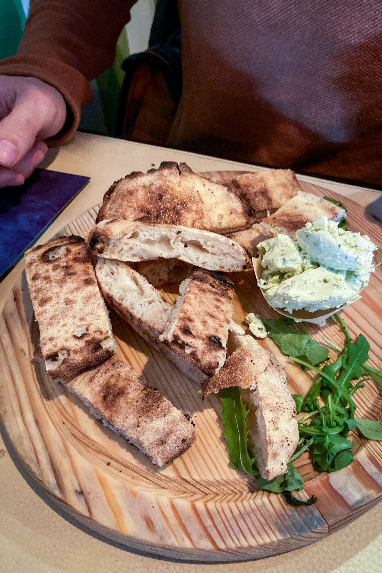 Gesneden brood met kruidenboter op een plank bij restaurant Ragu in Leiden